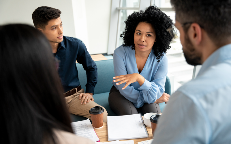 Imagem de capa de blog post sobre consultor de RH. Na foto, há quatros pessoas diversas conversando em um ambiente corporativo.